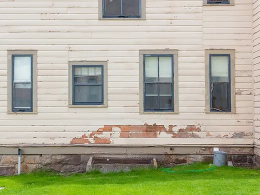 House wall before: weathered, peeling siding