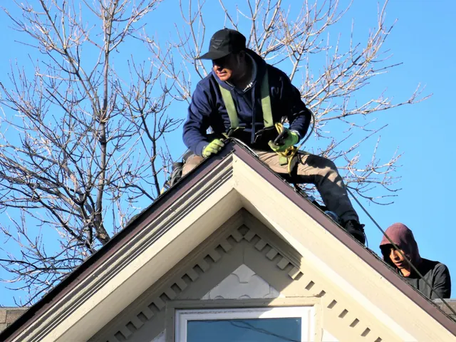 Roofers working on the ridge of a gable roof